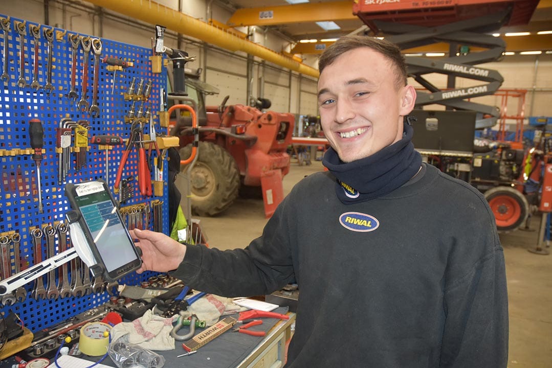 picture of a workshop where a smiling person presses a terminal