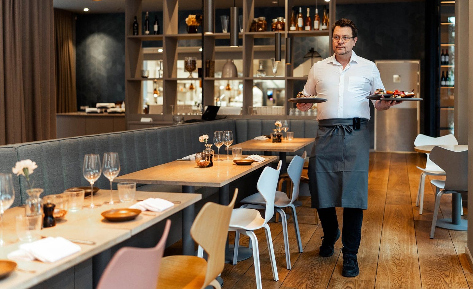 picture of a waiter bringing three dishes in a restaurant