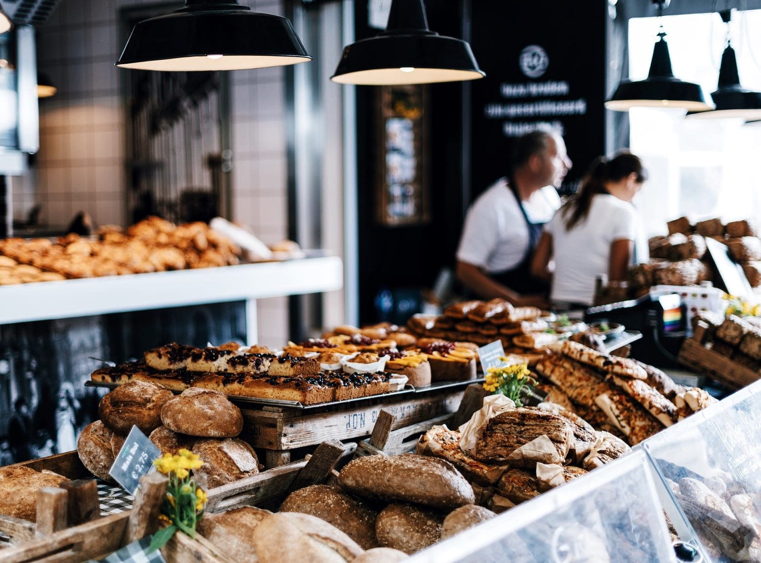 image of a bakery with lots of bread on display with two employees in the background