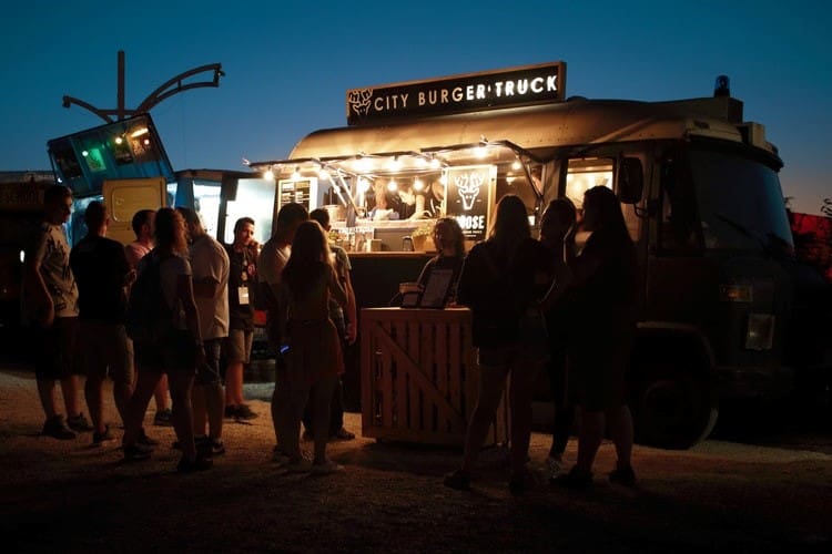 picture of people standing outside, in front of a city burger truck, in the evening