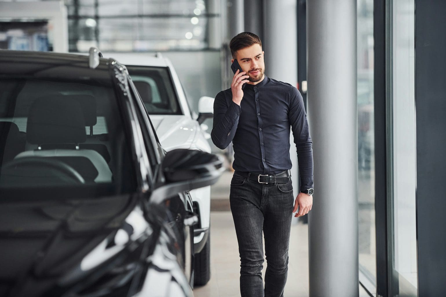 a man talking on the phone in a car dealership