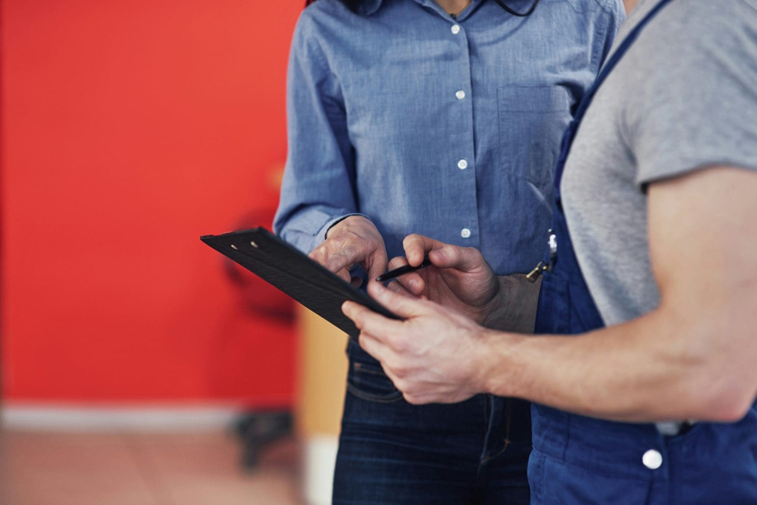 image of two people in a red room looking at a document they are about to sign