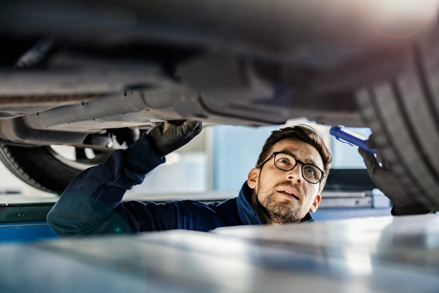 Workshop worker looking under a raised car