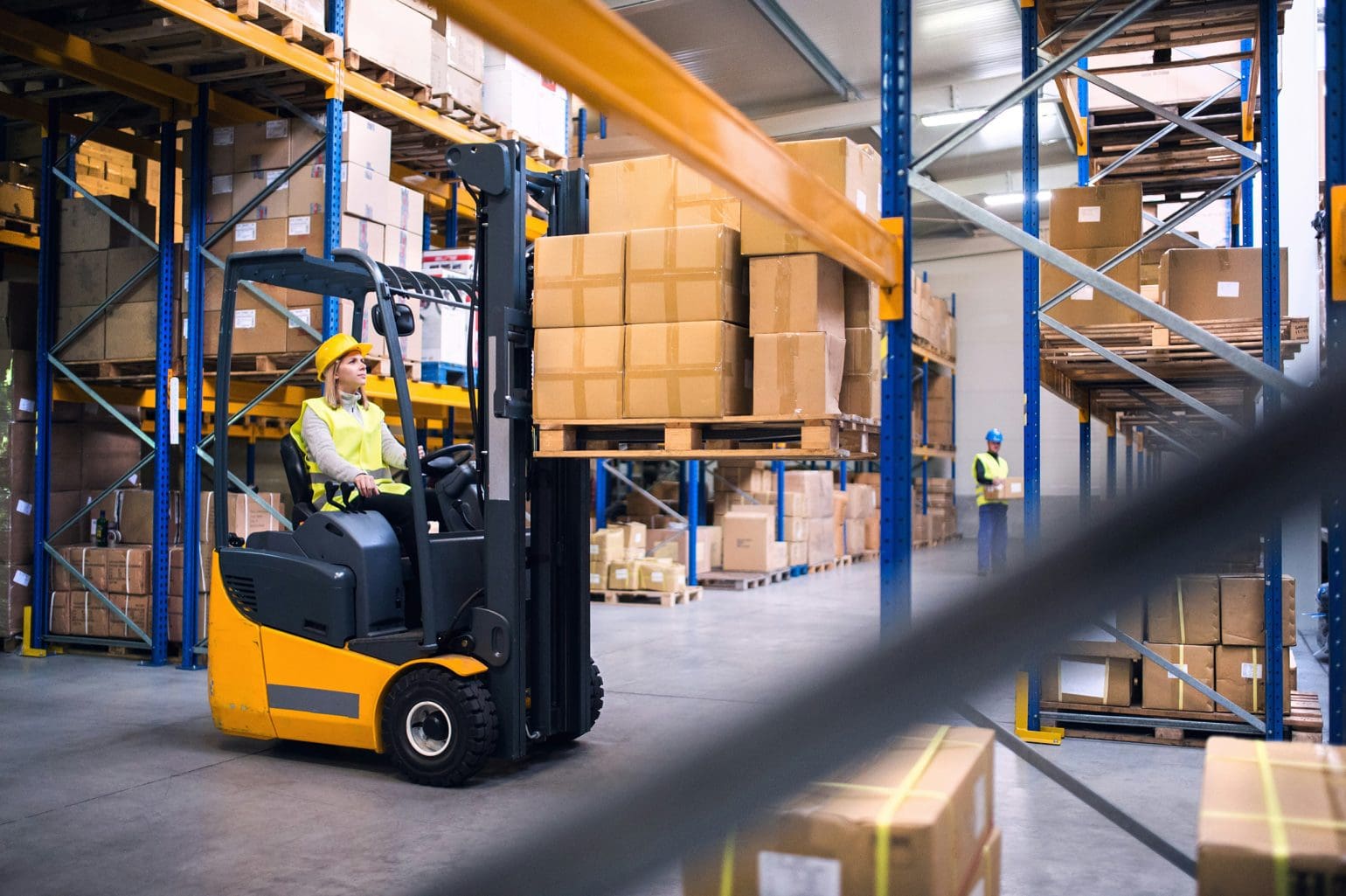 picture of a woman driving a forklift with packages into the warehouse
