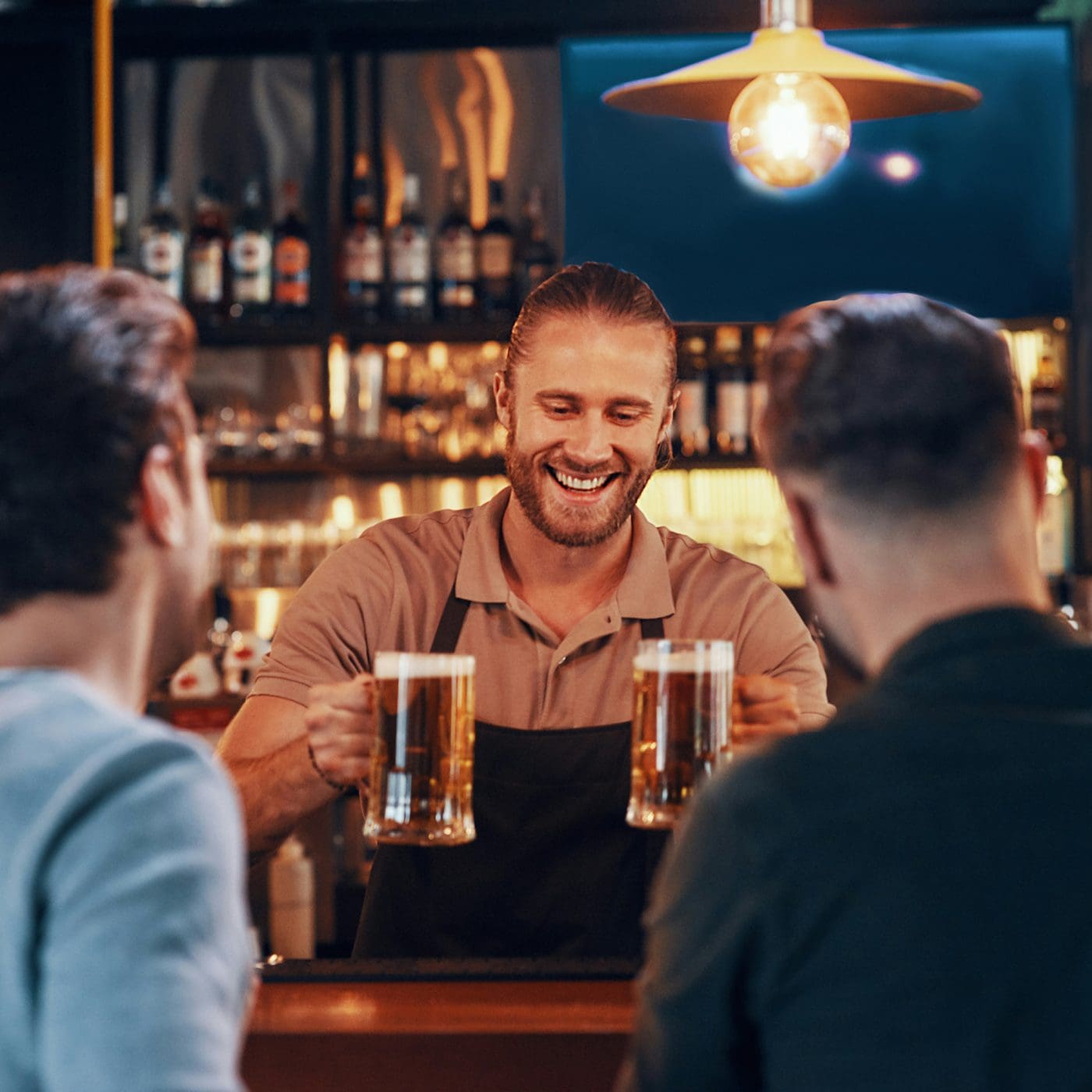 picture of a bartender serve two pints of beers with a smile