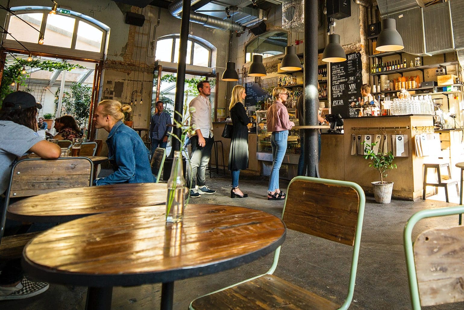 picture of a cafe where some people are standing in line and others are sitting and enjoying their drinks