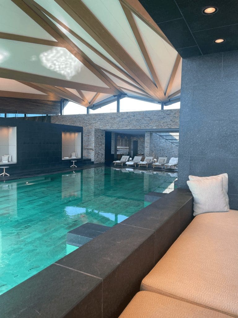 picture of an indoor pool with seating areas and lounge chairs