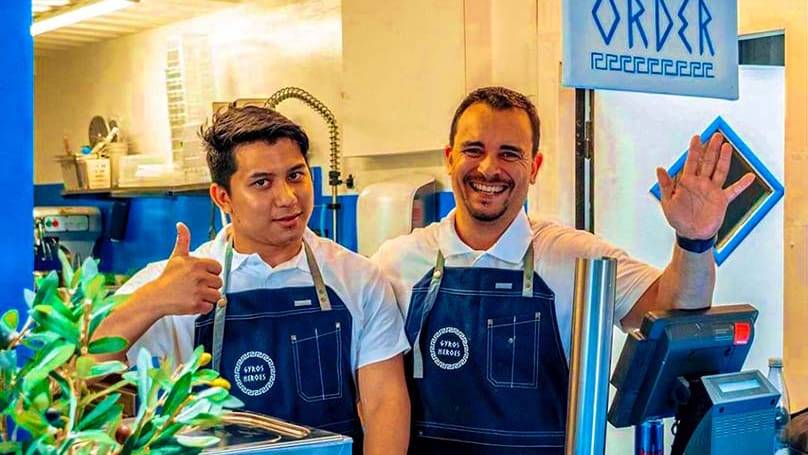 picture of two workers from Gyros Heros waving and smiling with a thumbs up