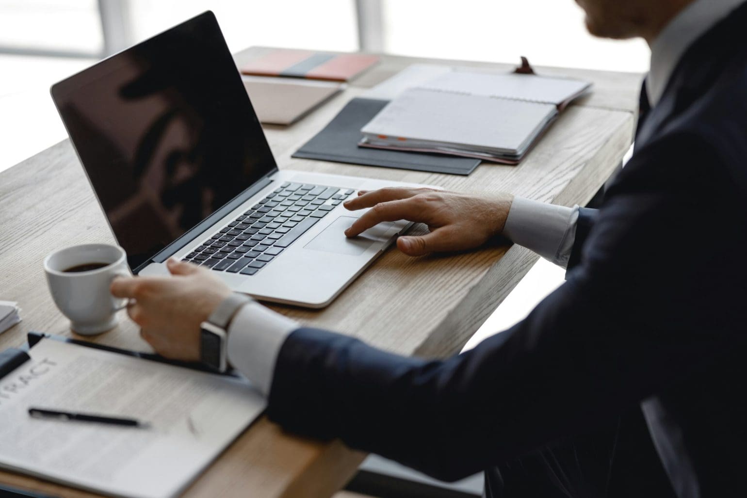 person sitting at their desk with laptop and a cup of coffee