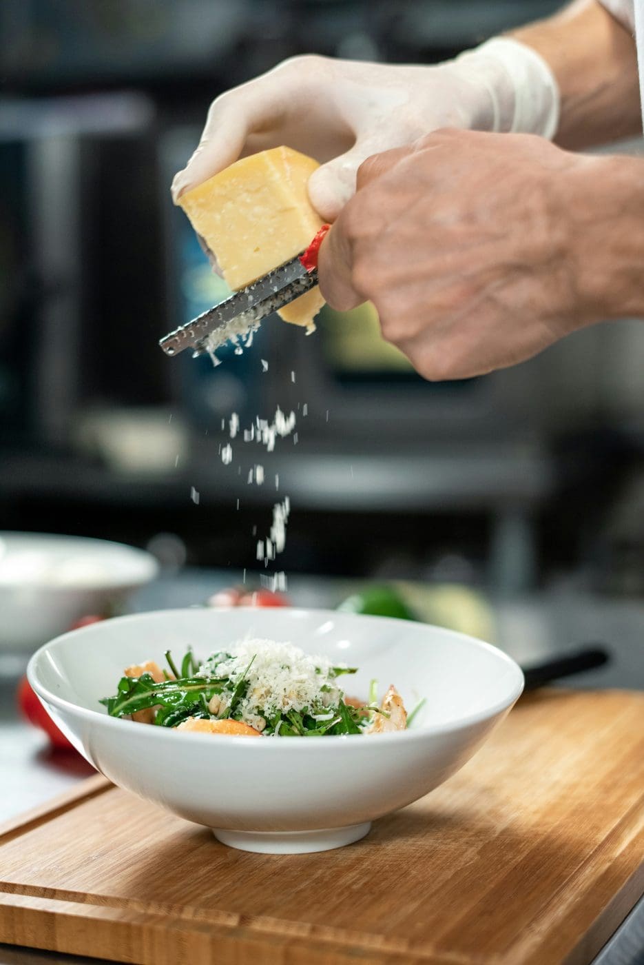 picture of a chef putting grated parmesan cheese in a dish