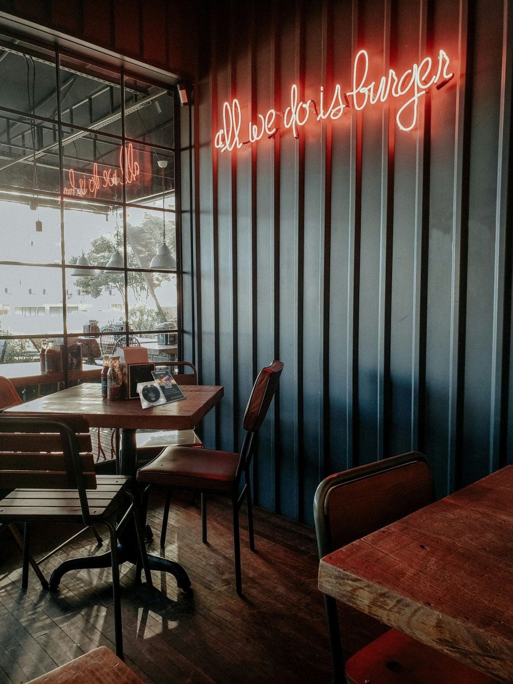 picture of the corner, inside a cafe near the window with a red neon sign