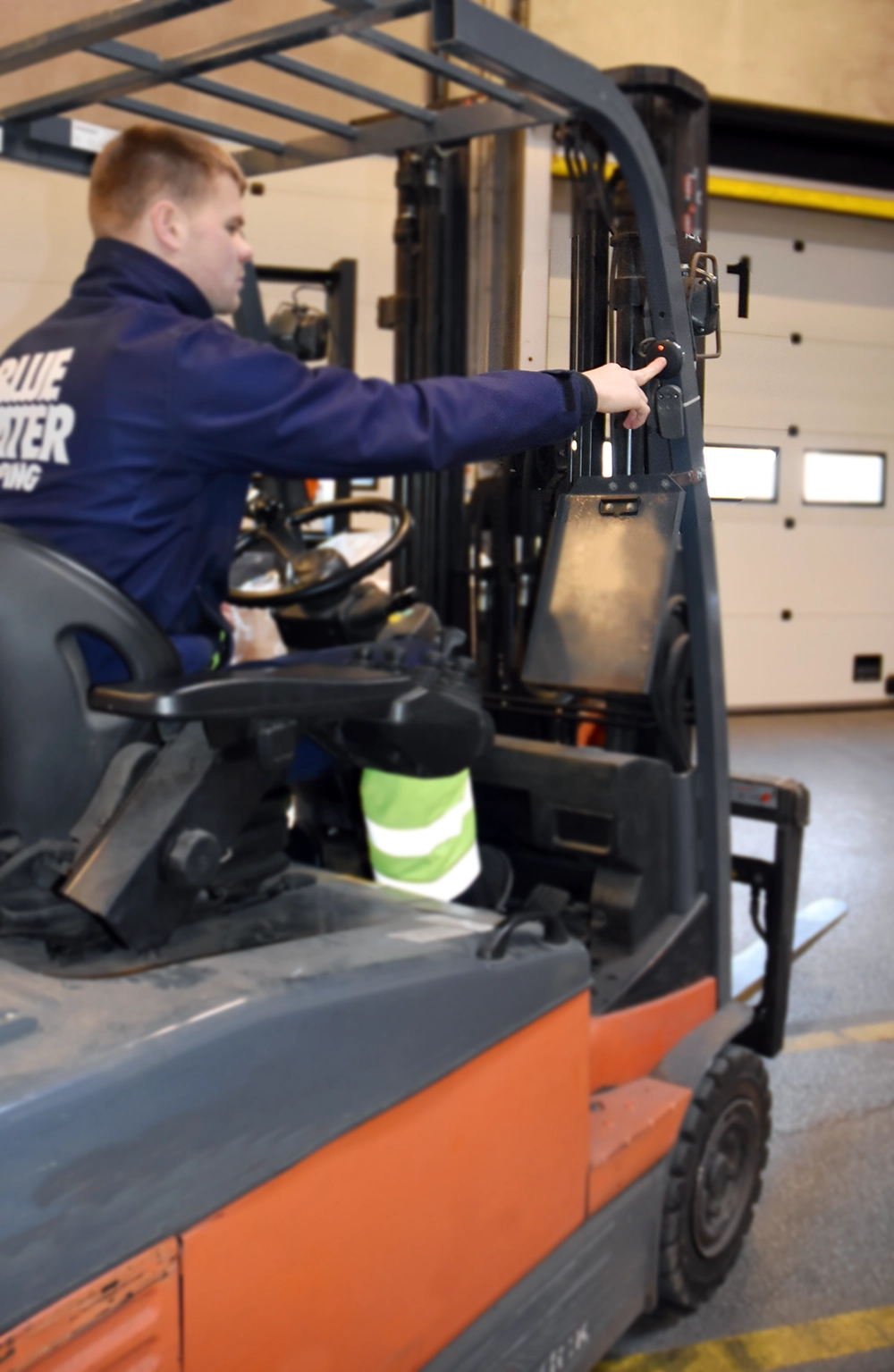 Young man in a forklift presses call button to request assistance – example of an efficient call system in an industrial environment.