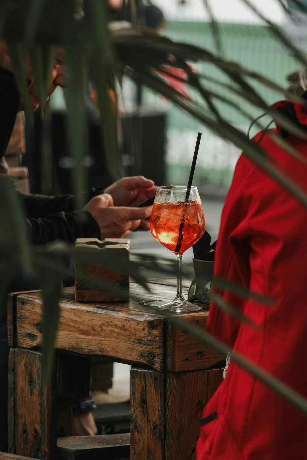 Drink in focus with guest using a mobile phone in the background – atmospheric image illustrating communication in a restaurant setting.