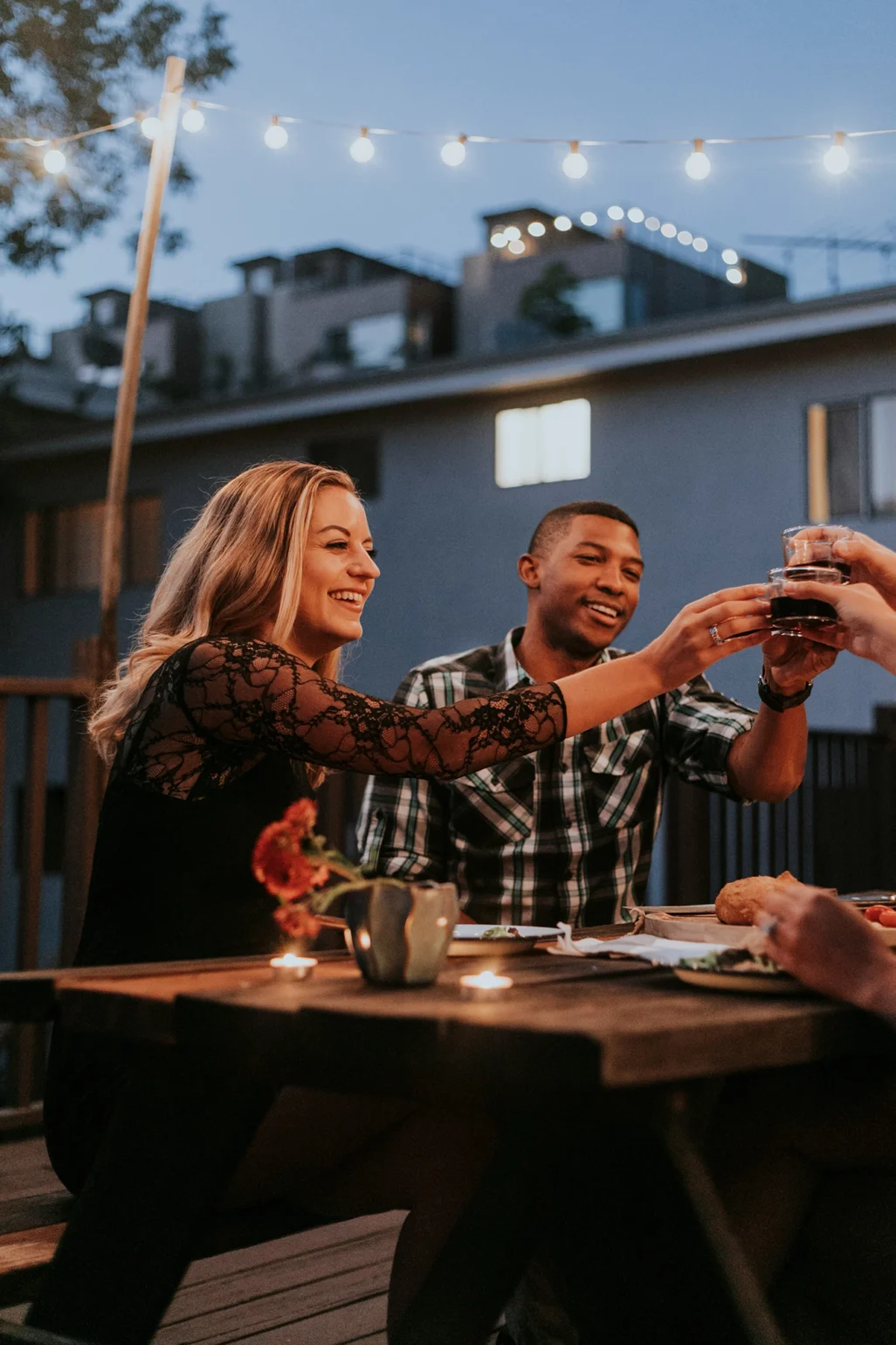 Couple toasting with friends over food in an outdoor food court – cozy evening and social dining atmosphere.