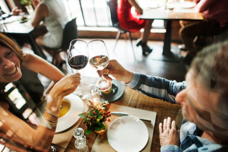 Guests toasting with wine at a restaurant table – illustrating relaxed atmosphere and excellent guest service